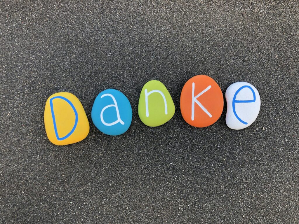 Danke, thank you in german language with colored stones over black volcanik sand