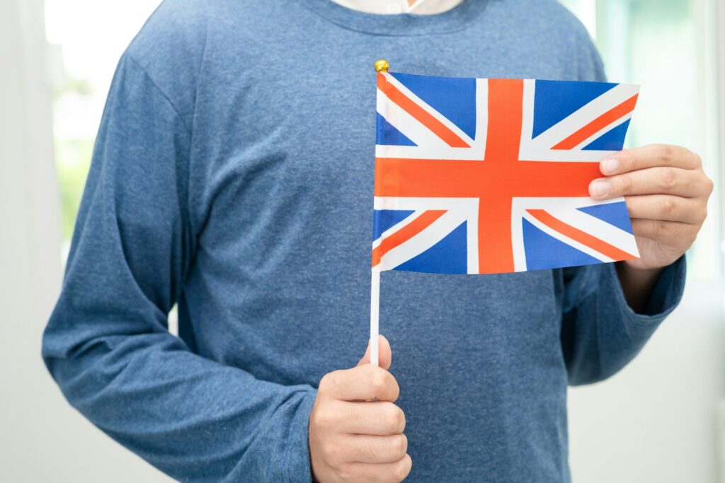 Learn English language, Asian teenage student hold UK flag in course at school.